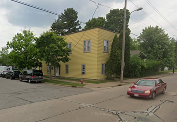 Wausau apartment for rent - A yellow house with a red car parked in front.