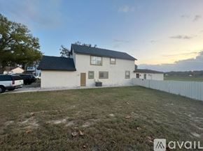 Orlando apartment for rent - A house with a white exterior and a black roof is surrounded by a white fence.