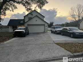 Orlando apartment for rent - A house with a garage and a driveway with two cars parked in front.
