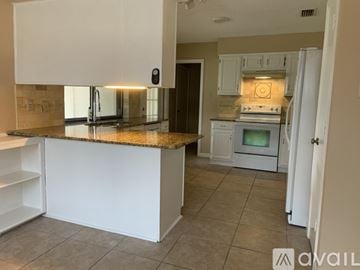 Plano house for rent - A kitchen with white cabinets and a granite countertop.