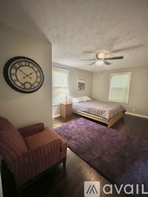 Decatur house for rent - A bedroom with a bed, a couch, and a clock on the wall.