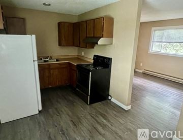 Kalispell apartment for rent - A kitchen with a white refrigerator, wooden cabinets, and a black stove top oven.