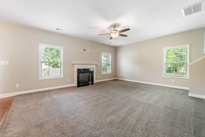 Sneads Ferry house for rent - A spacious living room with a fireplace and a ceiling fan.