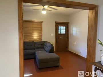 Wichita house for rent - A living room with a grey couch and a wooden door.