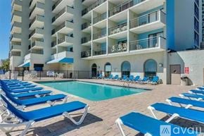 Myrtle Beach condo for rent - A pool area with sun loungers in front of a white building.