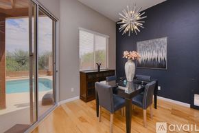 Oro Valley house for rent - A dining room with a glass table and chairs, a vase with flowers, and a painting on the wall.