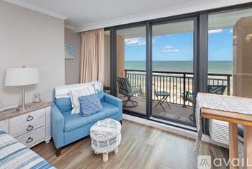 Myrtle Beach condo for rent - A living room with a blue couch and a view of the ocean through the sliding glass doors.