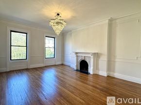 Boston apartment for rent - A hallway with wood floors and white walls leading to a door.