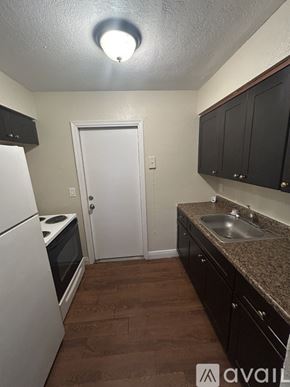 Belle Glade apartment for rent - A kitchen with brown flooring, white appliances, and black cabinets.