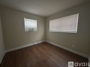 Belle Glade apartment for rent - A room with wooden floors and two windows with blinds.