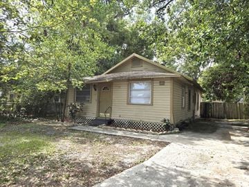 Lakeland house for rent - A small house with a porch is surrounded by trees.