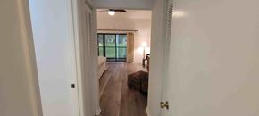 Hernando house for rent - A hallway with a door on the left and a bedroom with a bed and a lamp on the right.