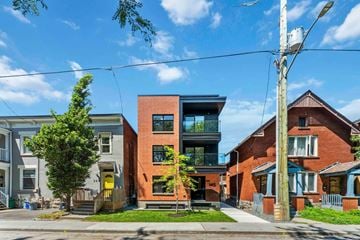 Ottawa apartment for rent - A modern red brick house with a glass balcony is in front of a row of older houses.