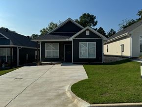 Little Rock house for rent - A black house with a white door and windows is surrounded by a green lawn.