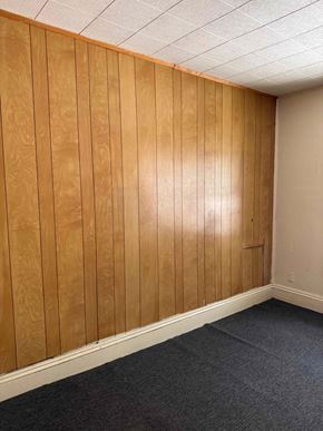 Syracuse apartment for rent - A room with wooden paneling and carpeted floor.