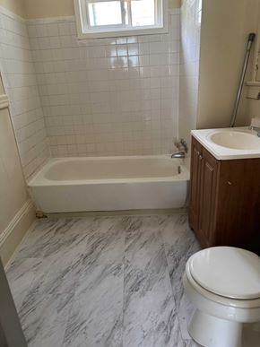 Syracuse apartment for rent - A white toilet sits next to a bathtub in a bathroom.