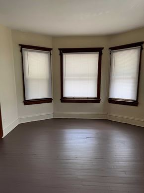 Syracuse apartment for rent - A room with wooden floors and three windows.