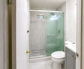 Monterey Park apartment for rent - A white toilet sits next to a walk-in shower with a glass door.
