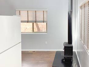 Show Low house for rent - A wood stove is in a corner of a room with a window.