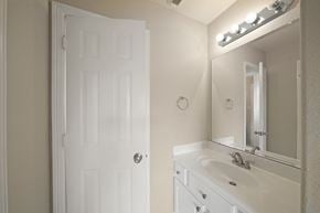 Houston house for rent - A white bathroom with a door, sink, and mirror.