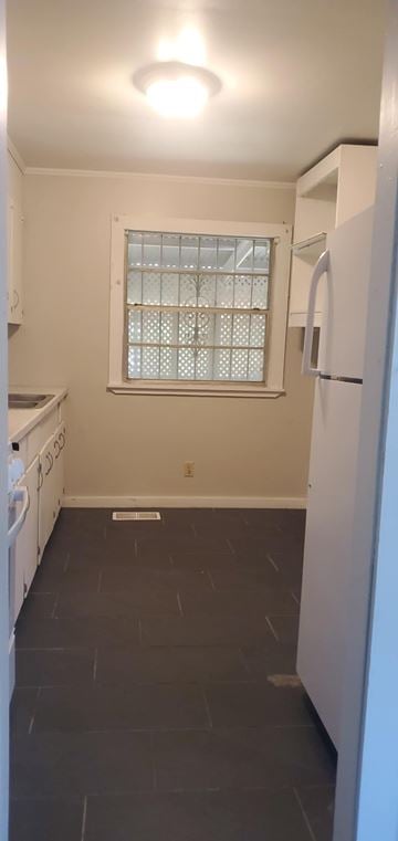 Hattiesburg house for rent - A kitchen with a white fridge and a window with blinds.