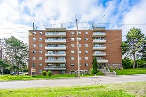 Oshawa apartment for rent - A large brick apartment building with a green lawn in front.