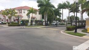 Homestead apartment for rent - A street view of a gated community with palm trees and a fire hydrant.