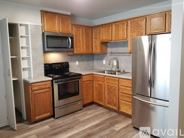 Pueblo apartment for rent - A kitchen with wooden cabinets and a stainless steel refrigerator.