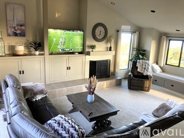 Santa Barbara house for rent - A living room with a leather couch, a coffee table, and a television playing a football game.