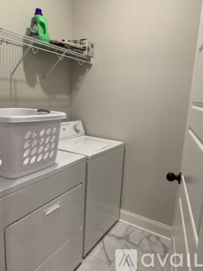 Oxford house for rent - A laundry room with a washer and dryer and a basket on top of the washer.