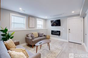 Providence apartment for rent - A living room with a grey couch, a brown coffee table, and a flat screen TV mounted on the wall.