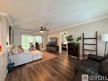 Sunrise house for rent - A living room with a grey sofa and a wooden floor.