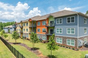 Conyers apartment for rent - A row of multi-colored townhouses with green lawns and trees.