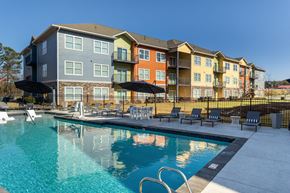 Conyers apartment for rent - A large swimming pool in front of a multi-story apartment building.