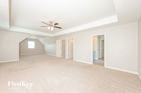 Winder house for rent - A spacious room with a ceiling fan and light fixture, carpeted floor, and a doorway leading to another room.