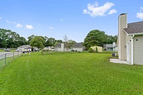 Jacksonville house for rent - A grassy backyard with a house and a fence.