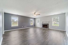 Jacksonville house for rent - A spacious living room with a fireplace and a ceiling fan.