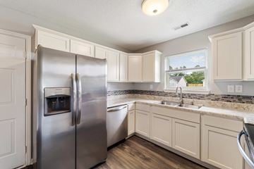 Jacksonville house for rent - A kitchen with a stainless steel refrigerator and white cabinets.