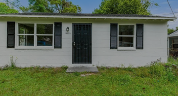 Jacksonville house for rent - A small white house with a black door and windows.