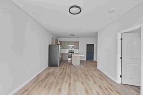 East Providence apartment for rent - A kitchen with a refrigerator, sink, and cabinets is visible through an open door.