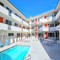 San Diego apartment for rent - A swimming pool in front of a white building with orange and blue accents.