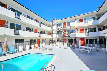 San Diego apartment for rent - A large white building with orange trim and a pool in the middle.
