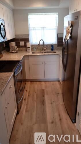 St. Pete Beach apartment for rent - A kitchen with wooden floors and white cabinets.