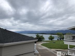 Polson condo for rent - A house with a view of a lake and mountains under a cloudy sky.
