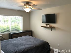 Polson condo for rent - A bedroom with a bed, a ceiling fan, and a television mounted on the wall.