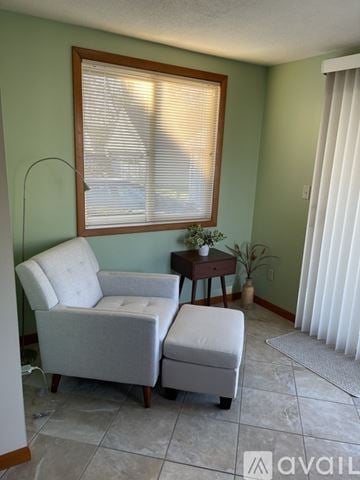 Grand Rapids house for rent - A living room with a chair, ottoman, and a small table with a plant on it.