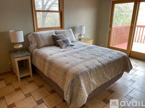 Polson house for rent - A bedroom with a large bed and a wooden nightstand with a lamp.