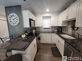 Polson apartment for rent - A kitchen with a black granite countertop and white cabinets.