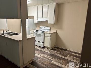El house for rent - A kitchen with white appliances and cabinets.