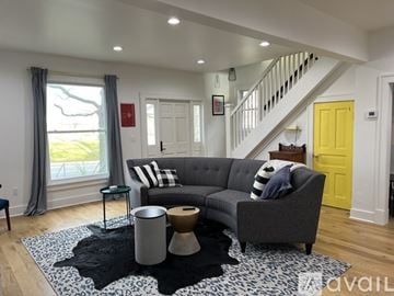 St. Joseph house for rent - A living room with a grey couch and a yellow door.